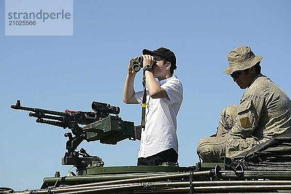 GREYMOUTH  NEW ZEALAND  NOVEMBER 18  2017: An unidentified schoolboy scans the horizon with binoculars at an open day run by the New Zealand armed forces. The machine gun is a Mag 58 GM