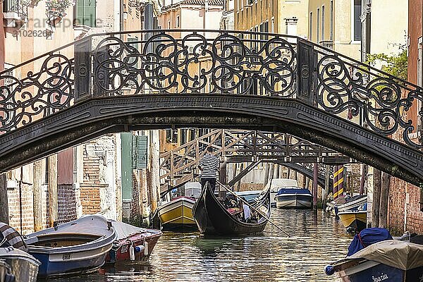 Venetian gondola with gondolier travelling on the canals of Venice  Venice  Italy  Europe