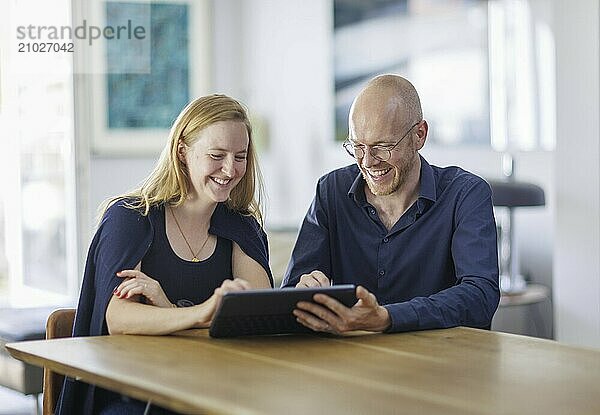 Symbolic photo. A woman and a man sit together at a table with a tablet and talk. Berlin  13.08.2024