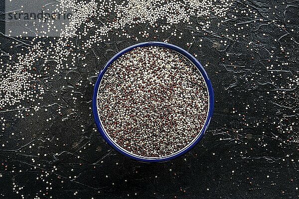 Quinoa mix. Mixed white  red and black quinoa seeds in a bowl  overhead flat lay shot on a black background