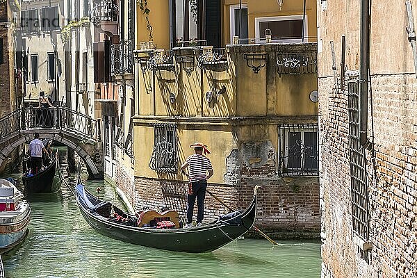 Venetian gondola with gondolier travelling on the canals of Venice  Venice  Italy  Europe