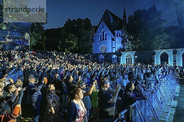 Large crowd at a night concert in front of a church  stage illuminated in blue  Klostersommer  Calw Hirsau  Black Forest  Germany  Europe