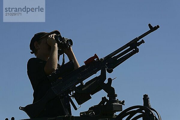 GREYMOUTH  NEW ZEALAND  NOVEMBER 18  2017: An unidentified schoolboy scans the horizon with binoculars at an open day run by the New Zealand armed forces. The machine gun is a Mag 58 GM