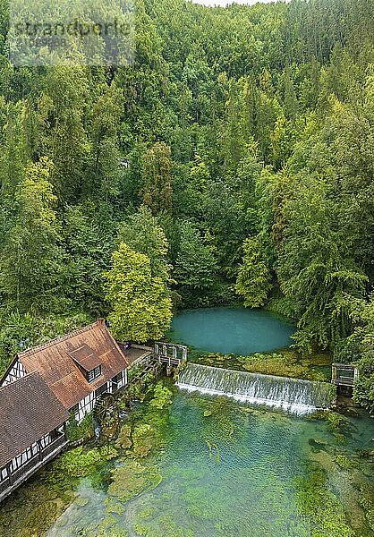 Blautopf Blaubeuren with industrial monument Hammerschmiede  source of the little river Blau in a landscape with forest. Karst spring  geotope and geopoint of the UNESCO Swabian Alb Geopark  tourist attraction. The popular excursion destination is now being thoroughly renovated and will therefore be closed to visitors until the end of 2028. Drone photo. Blaubeuren  Baden-Württemberg  Germany  Europe