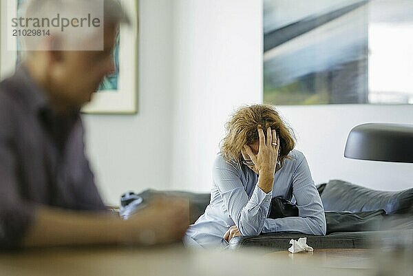 Symbolic photo on the subject of problems in a partnership. An older woman and an older man sitting at home. Berlin  13.08.2024