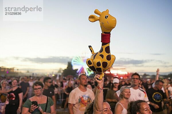 A festival visitor holds up an inflatable giraffe at the Highfield Festival on Friday  Störmthaler See  16/08/2024