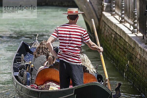 Venetian gondola with gondolier travelling on the canals of Venice  Venice  Italy  Europe