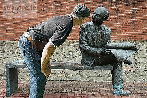 Funny  man looking at a bronze sculpture sitting on a bench