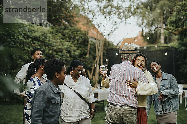 Happy family members greeting each other during social gathering at garden party