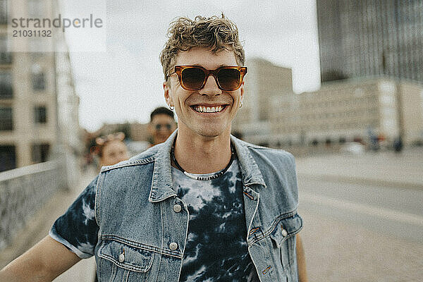 Portrait of happy young man in sunglasses walking on street