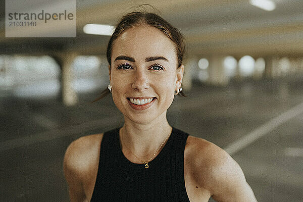 Portrait of beautiful smiling woman in black sleeveless casual at parking garage