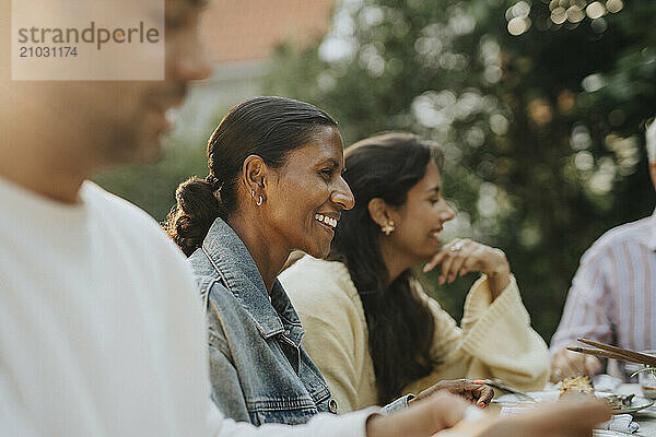 Happy mature woman having lunch with family members during social gathering