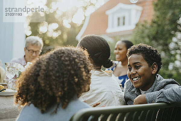 Smiling boy talking with female friend during dinner party in garden