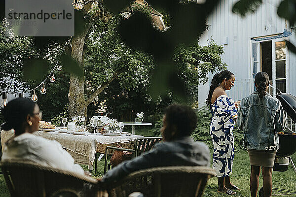 Female family members barbecuing during social gathering at garden party