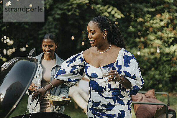 Mid adult woman barbecuing with female family member for garden party