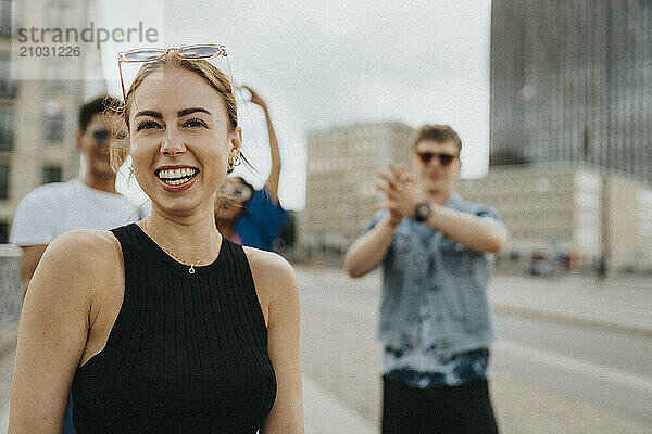 Happy young woman with friends spending leisure time on street in city