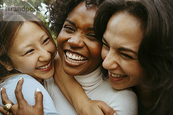 Close-up of cheerful female friends with arms around at dinner party