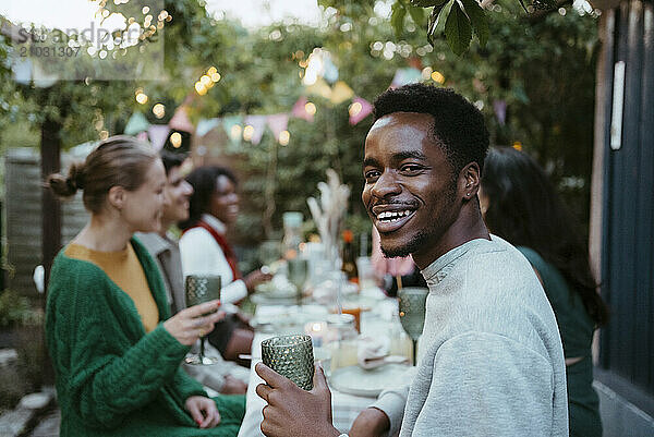 Side view portrait of smiling young man having fun with friends at party in back yard