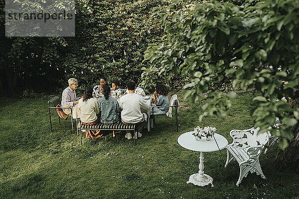 High angle view of male and female family members having dinner during social gathering in back yard