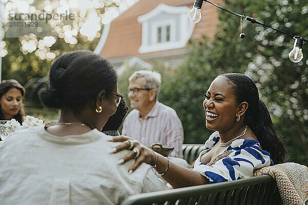 Cheerful mid adult woman having fun with female family member at garden party