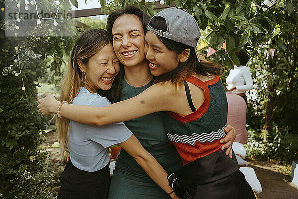 Smiling young woman embracing female friends at dinner party