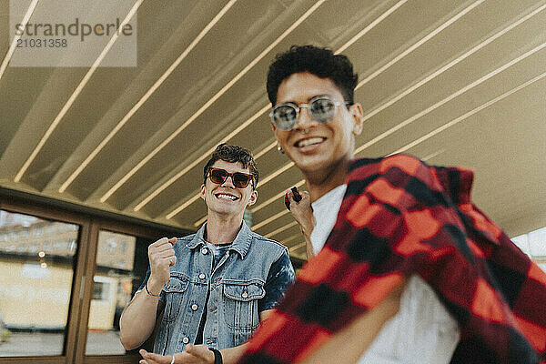 Low angle portrait of fashionable young male friends in sunglasses enjoying leisure time