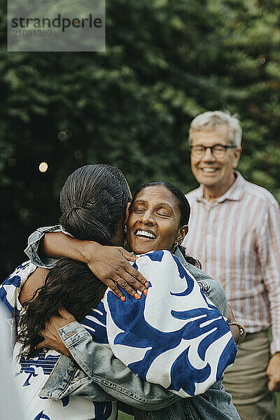 Female family members hugging each other at social gathering in back yard