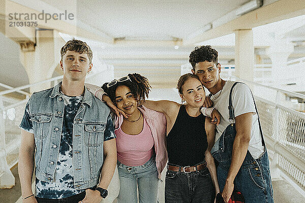 Portrait of fashionable young male and female friends posing at parking garage