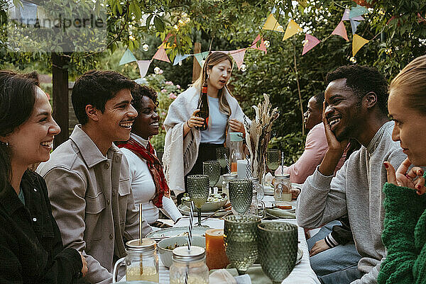 Group of cheerful male and female friends enjoying in dinner party at back yard