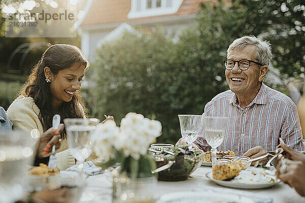 Active senior man having lunch with teenage family member at garden party