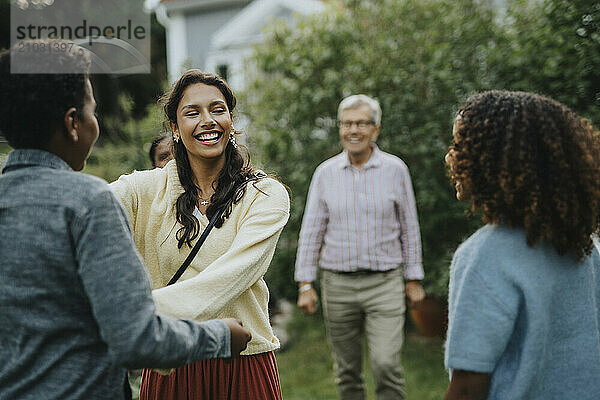 Cheerful teenage girl greeting family members at social gathering in back yard