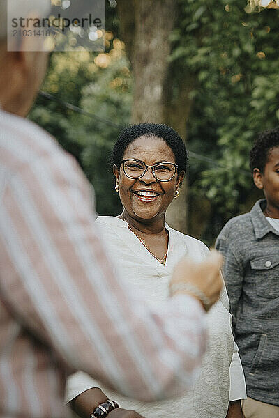 Cheerful senior woman having fun with family member in back yard