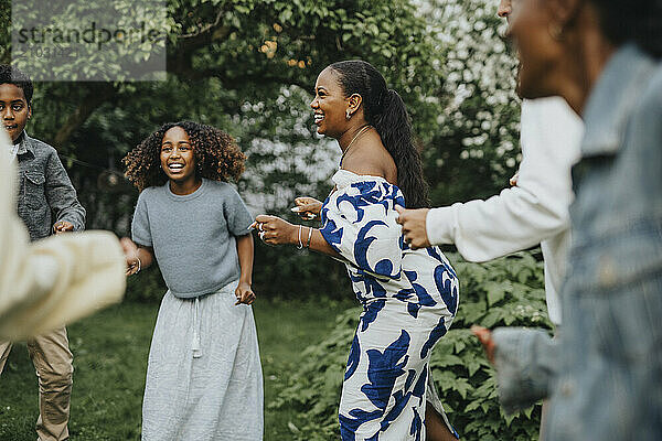 Cheerful mature woman dancing with male and female family members at garden party