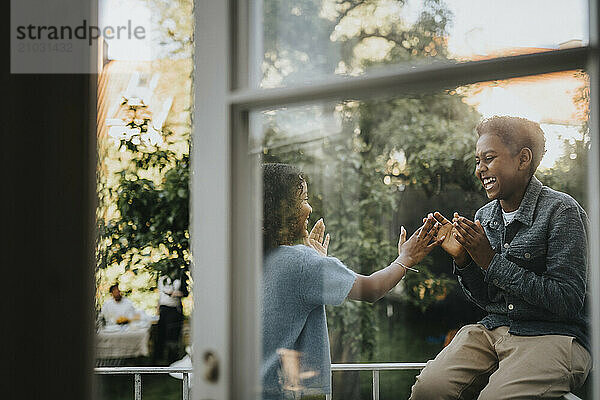 Cheerful boy playing with sister in balcony