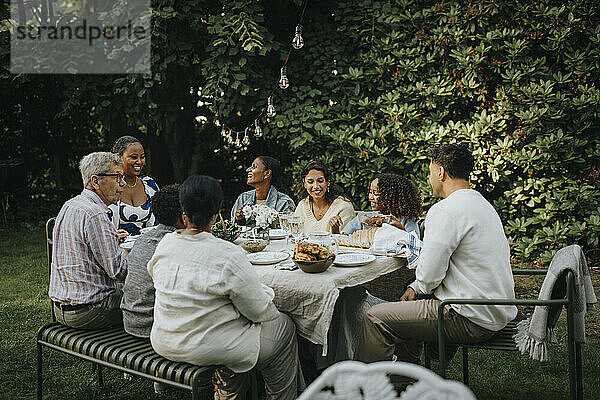 Male and female family members having lunch during social gathering at garden party