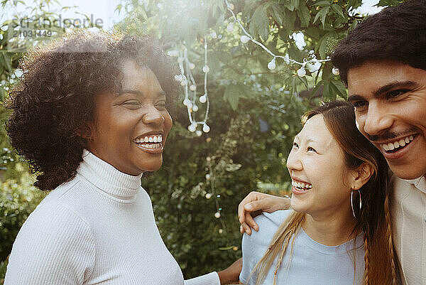 Cheerful woman having fun with male and female friends at dinner party