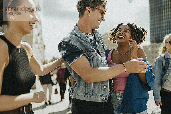 Happy young man having fun while walking with female friends at street