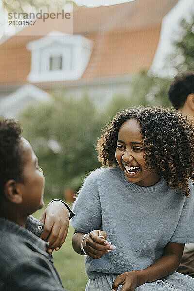 Carefree curly hair girl having fun with brother in back yard