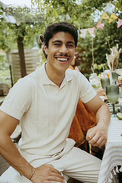 Portrait of smiling young man sitting at dining table during dinner party