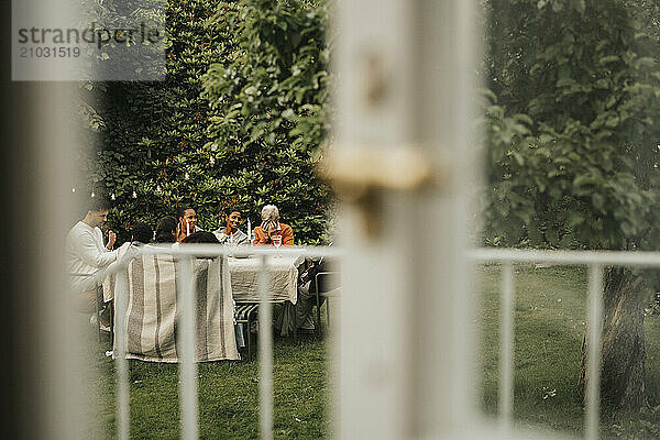 Male and female family members sitting near table for lunch at garden party