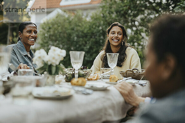 Cheerful mother and daughter having lunch during social gathering at garden party