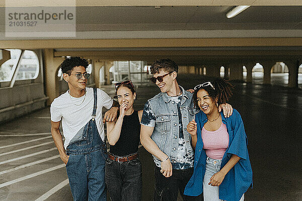 Cheerful fashionable male and female friends standing in parking garage