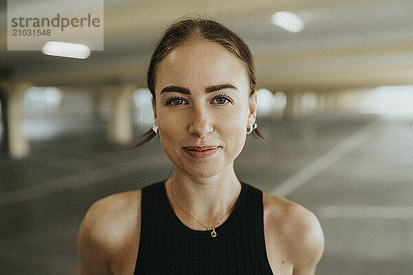 Portrait of beautiful young woman in black sleeveless casual at parking garage