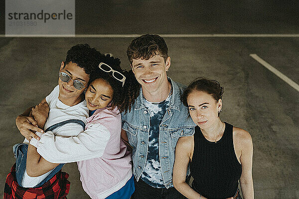 High angle portrait of male and female friends standing side by side in parking garage