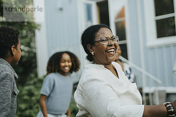 Happy active senior woman dancing with family members in back yard