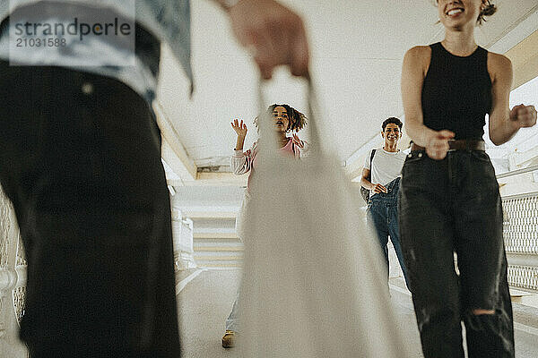 Happy young male and female friends dancing while walking at parking garage