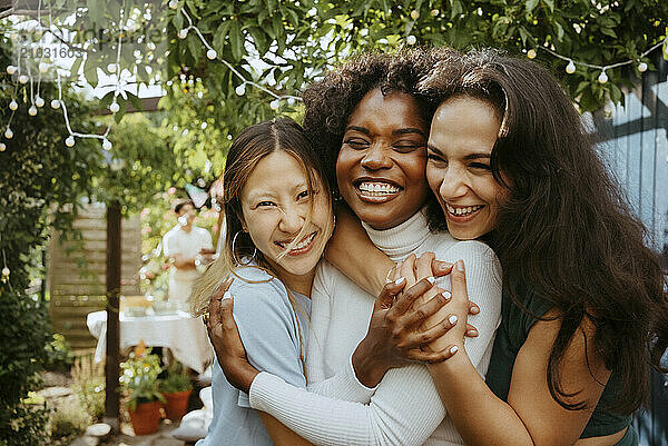 Smiling women embracing young female friend at dinner party