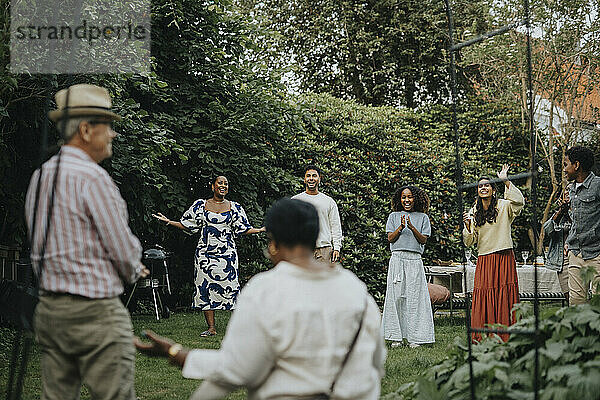 Cheerful male and female family members having fun during social gathering at garden party