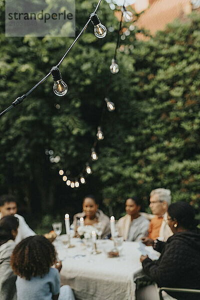 String lights with family celebrating celebrating dinner party in garden