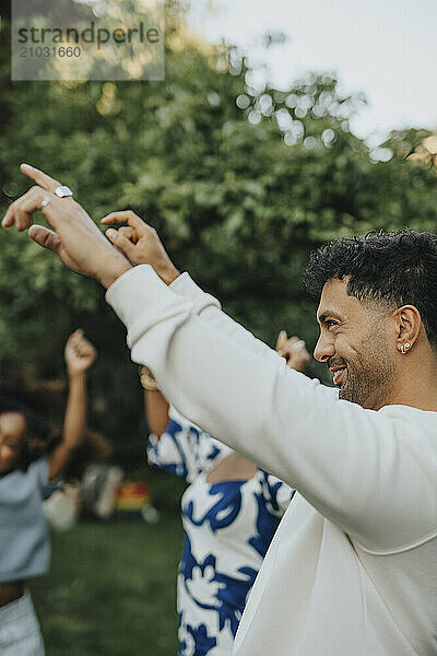 Happy mature man dancing and enjoying with family members in back yard